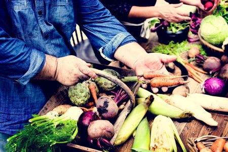 Closeup of hand buying fresh organic vegetable at market
